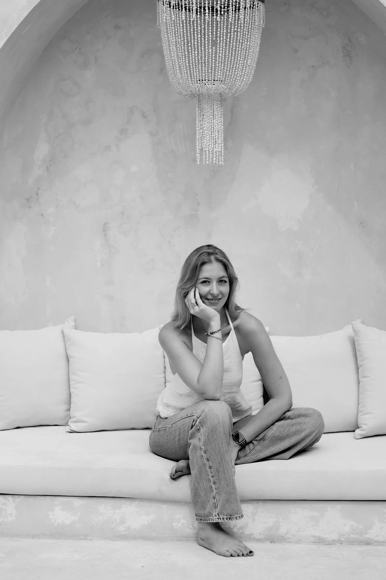 An-Sofie Rombouts of Wellmore Club, smiling on a white sofa in a calm wellness setting